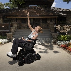 Ginger Lane holds a dance pose in her wheelchair in front of the Maddy Administration Building