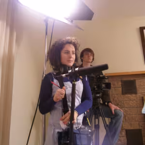 Sarah Nimeh stands behind a microphone on the set of a film. 