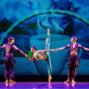 Three dancers dressed in stylized Arabian costumes pose onstage.