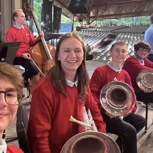 A smiling row of students with brass instruments.