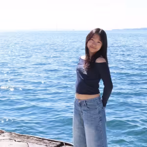 A student poses by the water on a sunny day.