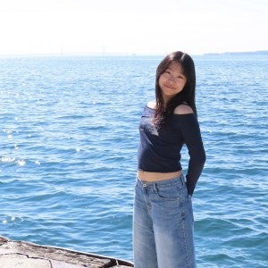 A student poses by the water on a sunny day.