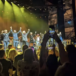 Paul Simon's band takes a bow at the end of a show in front of a cheering audience.