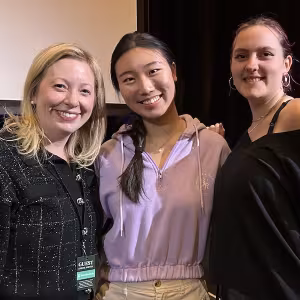 A guest artist poses with two students for a picture.