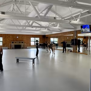 Dancers scatter around a studio space with large mirrors.