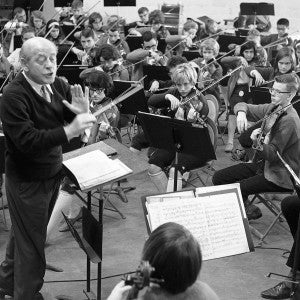 A conductor gestures with his stick to a group of student musicians.