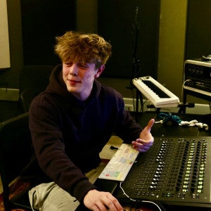 A student gestures while sitting at the piano. 