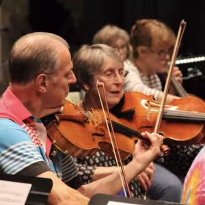 Musicians play violins in a string orchestra.