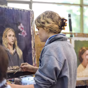 A student works on a painted self portrait 