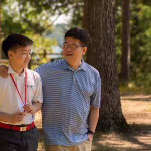 An arts camp student walks through campus with their parent