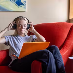 A music student sits down at their laptop for an online class