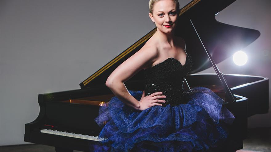 a photo of kara huber posed in front of an open grand piano